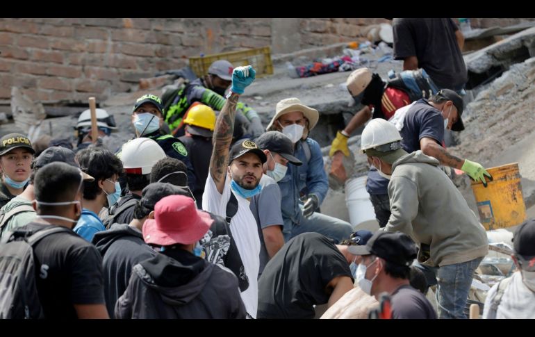 Voluntarios levantan los brazos para pedir silencio durante las labores de búsqueda en edificios derrumbados por el terremoto en Pereira, Colombia. EFE/C. Ortega