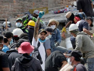 Voluntarios levantan los brazos para pedir silencio durante las labores de búsqueda en edificios derrumbados por el terremoto en Pereira, Colombia. EFE/C. Ortega