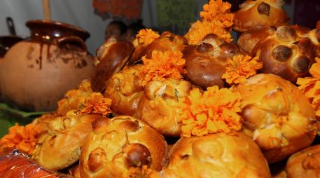 Entre flores, veladoras, fotografías, papel picado de colores y otros elementos, también aparece el pan de muerto. NTX / ARCHIVO