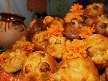 Entre flores, veladoras, fotografías, papel picado de colores y otros elementos, también aparece el pan de muerto. NTX / ARCHIVO