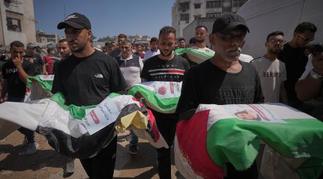 Dolientes cargan los cuerpos, cubiertos con banderas, de palestinos muertos en ataques israelíes durante la guerra contra Hamás, cuyos restos fueron recuperados recientemente de entre los escombros, en Ciudad de Gaza, el jueves 20 de agosto de 2026. Foto AP/J. Alshrafi