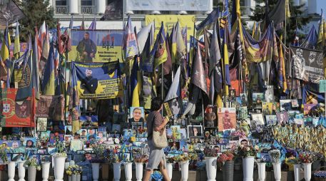 Una mujer pasa frente a un altar con fotografías de soldados ucranianos caídos en combate. AFP