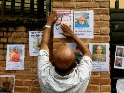 Un hombre cuelga la fotografía de uno de sus conocidos, con la esperanza de que sea identificado con vida por el gobierno nepalí. EFE/N. Shrestha