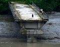 Un grupo de personas permanece sobre los restos de un puente que cruzaba el río Trishuli y fue arrastrado por una crecida repentina, en el distrito de Dhading, Nepal, el domingo 30 de agosto de 2026. AP/N. Shrestha