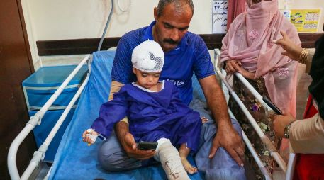 Un hombre acompaña a un niño que, según la prensa iraní, resultó herido en el ataque a una vivienda donde se celebraba una boda en la provincia de Kuhestak. AP/R. Poudat