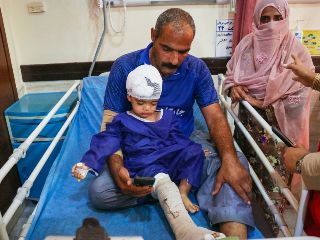 Un hombre acompaña a un niño que, según la prensa iraní, resultó herido en el ataque a una vivienda donde se celebraba una boda en la provincia de Kuhestak. AP/R. Poudat