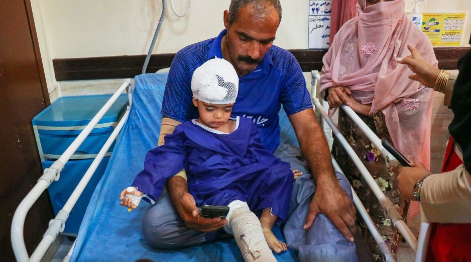 Un hombre acompaña a un niño que, según la prensa iraní, resultó herido en el ataque a una vivienda donde se celebraba una boda en la provincia de Kuhestak. AP/R. Poudat