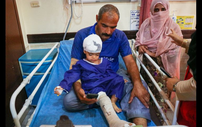 Un hombre acompaña a un niño que, según la prensa iraní, resultó herido en el ataque a una vivienda donde se celebraba una boda en la provincia de Kuhestak. AP/R. Poudat