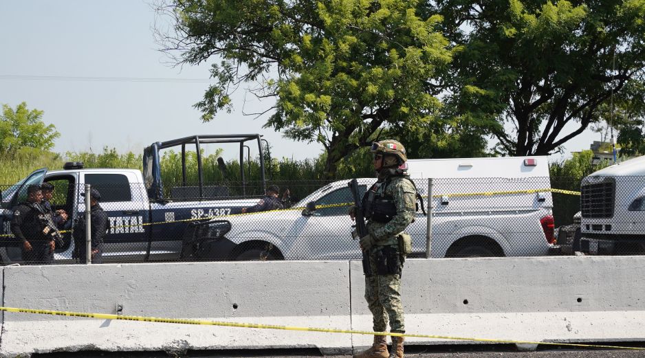 Un agente de la Policía Federal permanece junto a vehículos policiales cerca del lugar donde se halló el cuerpo del diputado Zenyazen Escobar García. AFP/V. Razo