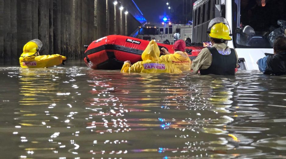 Brigadistas municipales utilizan una embarcación ligera para rescatar a pasajeros  que se quedaron varados en un paso a desnivel inundado. ESPECIAL