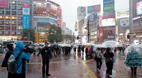 Un equipo de televisión realiza un reportaje cerca del cruce de Shibuya bajo las fuertes lluvias provocadas por el tifón Dujuan en Tokio, Japón, el 21 de septiembre de 2026. EFE/F. ROBICHON