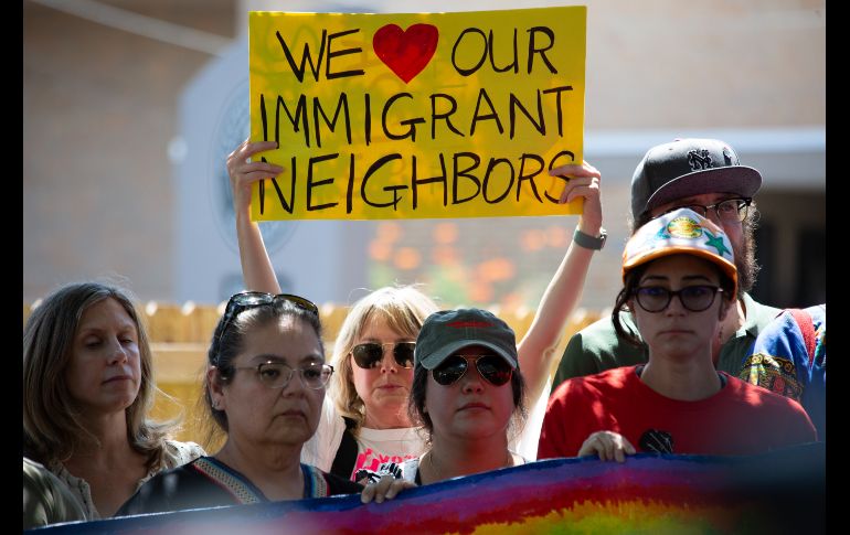 Una mujer sostiene un cartel este lunes en el lugar donde un inmigrante venezolano recibió un disparo por la espalda de un agente del ICE el pasado domingo en Austin. EFE/C. Ramírez