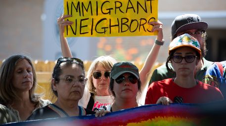 Una mujer sostiene un cartel este lunes en el lugar donde un inmigrante venezolano recibió un disparo por la espalda de un agente del ICE el pasado domingo en Austin. EFE/C. Ramírez