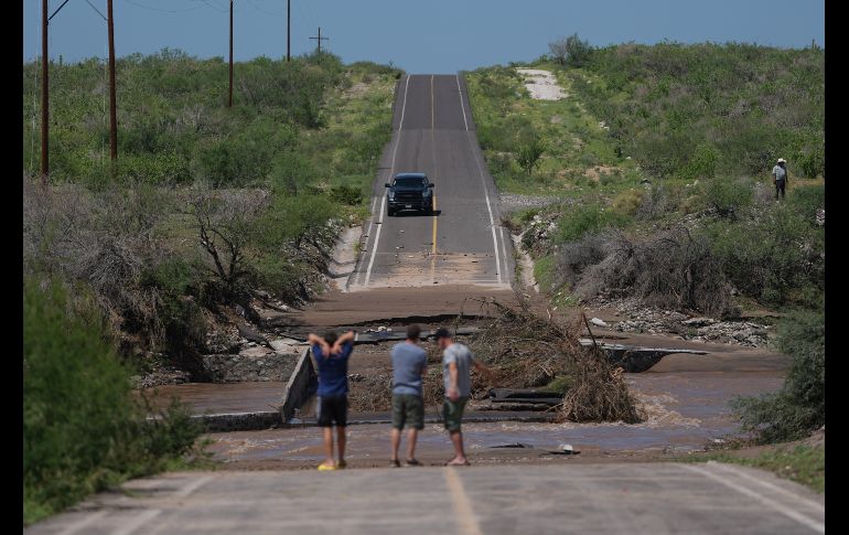 Varios hombres inspeccionan una carretera dañada por la crecida de un río a lo largo de la ruta hacia Las Barrancas, en Baja California Sur. AP/E. Verdugo