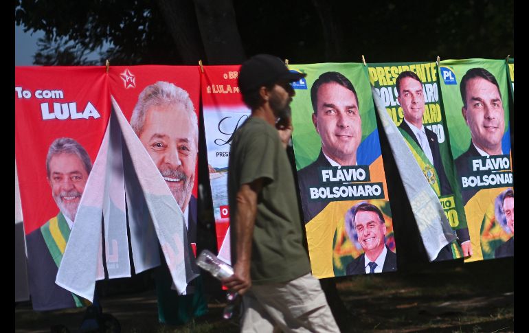 Un hombre camina frente a una tienda informal de banderas con la imagen del presidente de Brasil y candidato a la reelección, Luiz Inácio Lula da Silva, y del candidato presidencial, Flávio Bolsonaro. EFE/A. Borges