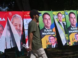 Un hombre camina frente a una tienda informal de banderas con la imagen del presidente de Brasil y candidato a la reelección, Luiz Inácio Lula da Silva, y del candidato presidencial, Flávio Bolsonaro. EFE/A. Borges