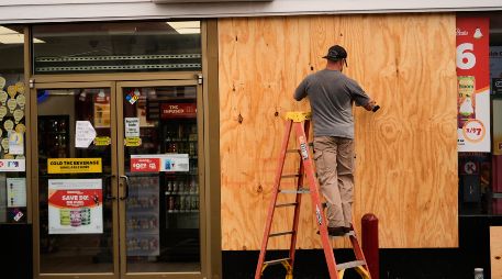 Jason Coffey coloca tablones en una tienda en una gasolinera mientras el huracán Isaías se acerca a Pensacola Beach, Florida. AP/G. Herbert