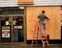 Jason Coffey coloca tablones en una tienda en una gasolinera mientras el huracán Isaías se acerca a Pensacola Beach, Florida. AP/G. Herbert