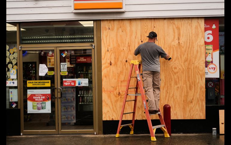 Jason Coffey coloca tablones en una tienda en una gasolinera mientras el huracán Isaías se acerca a Pensacola Beach, Florida. AP/G. Herbert