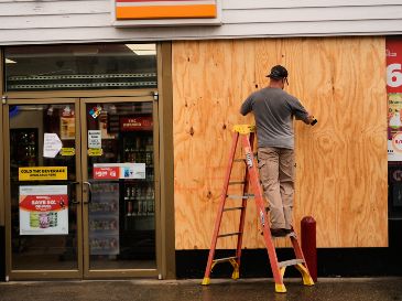 Jason Coffey coloca tablones en una tienda en una gasolinera mientras el huracán Isaías se acerca a Pensacola Beach, Florida. AP/G. Herbert