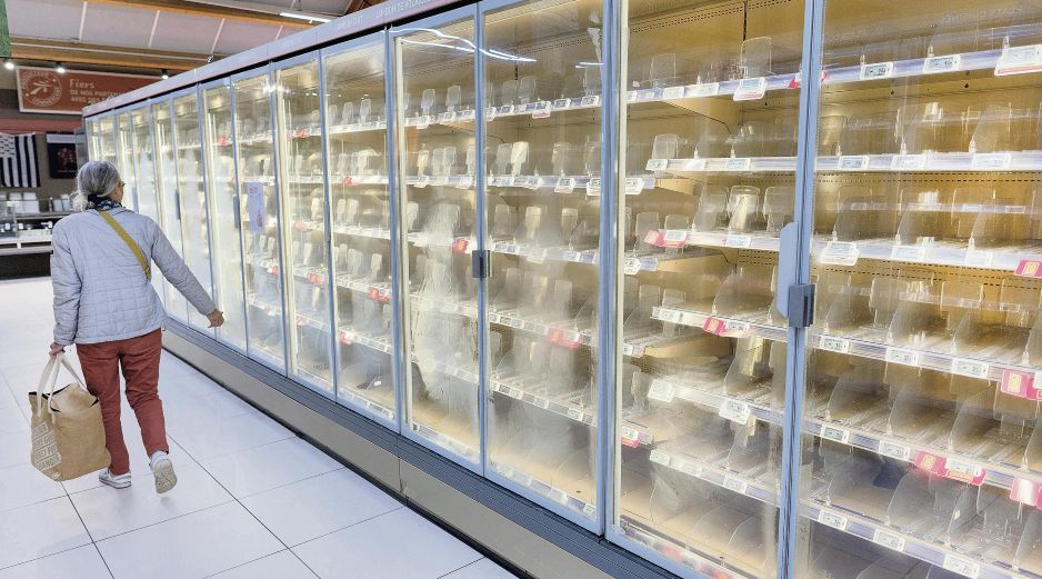 Una mujer camina ante los refrigeradores vacíos de Intermarché, una de las cadenas más afectadas. AFP