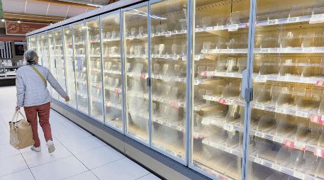 Una mujer camina ante los refrigeradores vacíos de Intermarché, una de las cadenas más afectadas. AFP