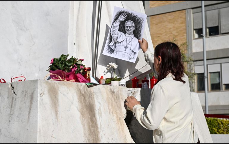 Una mujer coloca un retrato del Papa León al pie de la estatua del Papa Juan Pablo II, frente al Hospital Universitario Agostino Gemelli. EFE/EPA/R. Antinianiefe