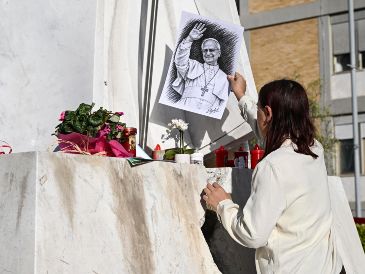 Una mujer coloca un retrato del Papa León al pie de la estatua del Papa Juan Pablo II, frente al Hospital Universitario Agostino Gemelli. EFE/EPA/R. Antinianiefe