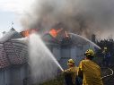 Bomberos trabajan para apagar fuego en una casa durante el incendio 