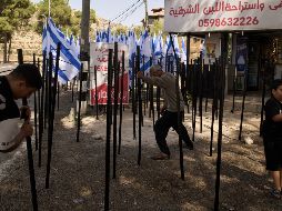 El palestino Mouayad Oweis y sus hijos tratan de retirar astas de bandera colocadas por colonos israelíes para bloquear el acceso a su cafetería en el poblado de al-Lubban al-Sharqiya, Cisjordania, el jueves 8 de octubre de 2026. AP/ Leo Correa