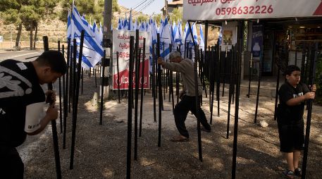 El palestino Mouayad Oweis y sus hijos tratan de retirar astas de bandera colocadas por colonos israelíes para bloquear el acceso a su cafetería en el poblado de al-Lubban al-Sharqiya, Cisjordania, el jueves 8 de octubre de 2026. AP/ Leo Correa