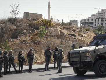 Soldados israelíes se reúnen en el lugar de un ataque a tiros perpetrado por hombres armados palestinos en un cruce cerca de Hebrón, en la Cisjordania ocupada. AP/M. Illean