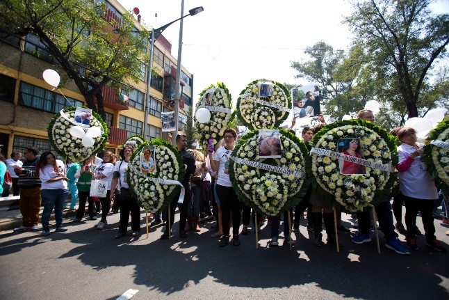 Residents of building 1C at the Multifamiliar Tlalpan housing complex - Residents of building 1C at the Multifamiliar Tlalpan housing complex in Mexico City carry wreaths and photos of the nine people who were killed there when it collapsed in a magnitude 7.1 earthquake, on the one month anniversary of the temblor, Thursday, Oct. 19, 2017. At the sites of other collapsed buildings, people raised their fists in a three-minute silent salute, mimicking the gesture made to call for silence as rescuers search for survivors in the rubble. (AP Photo/Rebecca Blackwell) Mexico Earthquake Anniversary