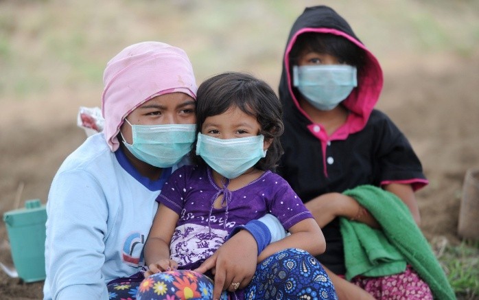 Una mujer indonesia y sus hijos usan mascarillas como medida de protección. AFP/S. Tumbelaka