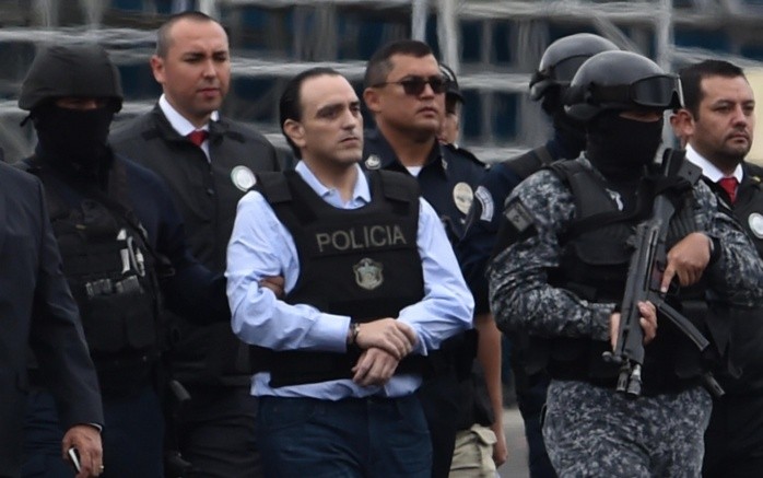 Roberto Borge (c) es escoltado en el aeropuerto de la Ciudad de Panamá. AFP/R. Arangua