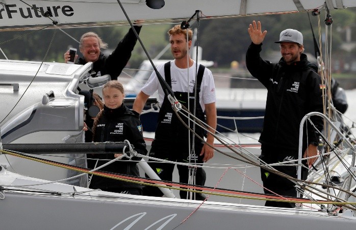 Swedish climate activist Greta Thunberg (2L), her father Svante Thunberg (L), and skippers Pierre Casiraghi (2R) and Boris Herrmann wave from aboard the Malizia II IMOCA class sailing yacht, off the coast of Plymouth, southwest England, on August 14, 2019, as she prepares to start her journey across the Atlantic to New York where she will attend the UN Climate Action Summit next month. A year after her school strike made her a figurehead for climate activists, Greta Thunberg believes her uncompromising message about global warming is getting through -- even if action remains thin on the ground. The 16-year-old Swede, who sets sail for New York this week to take her message to the United States, has been a target for abuse but sees that as proof she is having an effect. / AFP / POOL / Kirsty Wigglesworth BRITAIN-SWEDEN-ENVIRONMENT-CLIMATE-THUNBERG