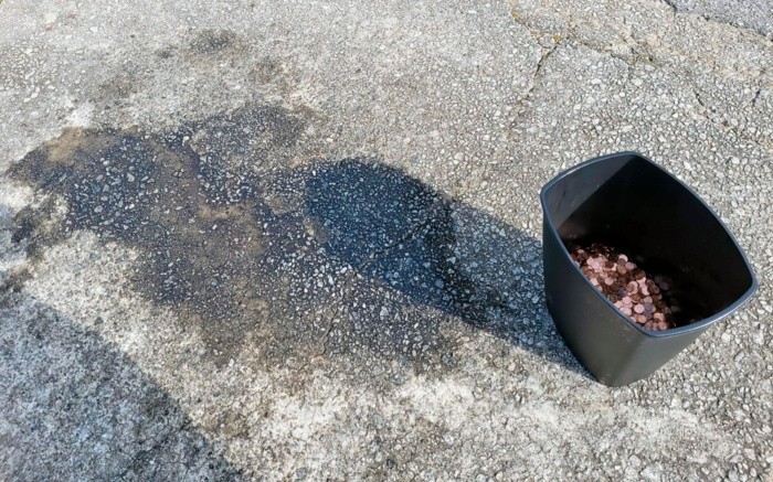 This image provided by Olivia Oxley shows a stain on the pavement, March 20, 2021 in Fayetteville, Ga. A Georgia man said his former employer owed him a pretty penny, $915 to be exact, after leaving his job in November. But Andreas Flaten said he was shocked to see his final payment: 90,000 oil or grease covered pennies, at the end of his driveway earlier this month, news outlets reported. Atop the pile was an envelope with Flaten's final paystub and an explicit parting message. (Olivia Oxley via AP)-AP PROVIDES ACCESS TO THIS THIRD PARTY PHOTO SOLELY TO ILLUSTRATE NEWS REPORTING OR COMMENTARY ON FACTS DEPICTED IN IMAGE; MUST BE USED WITHIN 14 DAYS FROM TRANSMISSION; NO ARCHIVING; NO LICENSING; MANDATORY CREDIT