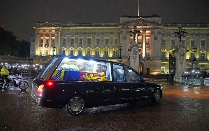 The hearse carrying the coffin of Queen Elizabeth II arrives at Buckingham Palace, London, Tuesday, Sept. 13, 2022, from where it will rest overnight in the Bow Room. (Gareth Fuller/Pool Photo via AP)-POOL PHOTO